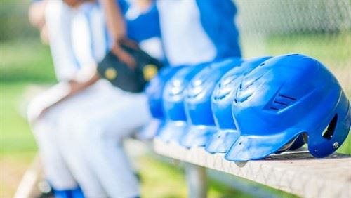 Picture of baseball helmets with the team in the background.